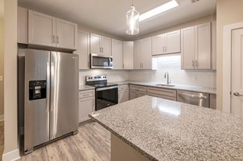 A kitchen with a granite countertop and stainless steel appliances.